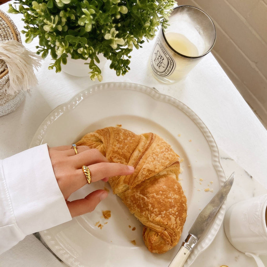croissant breakfast and hand with gold rings