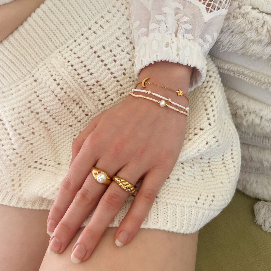 gold beaded jewellery stack on white knit shorts