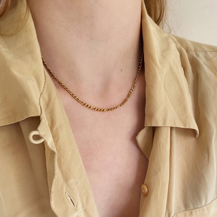 woman wearing gold figaro chain necklace