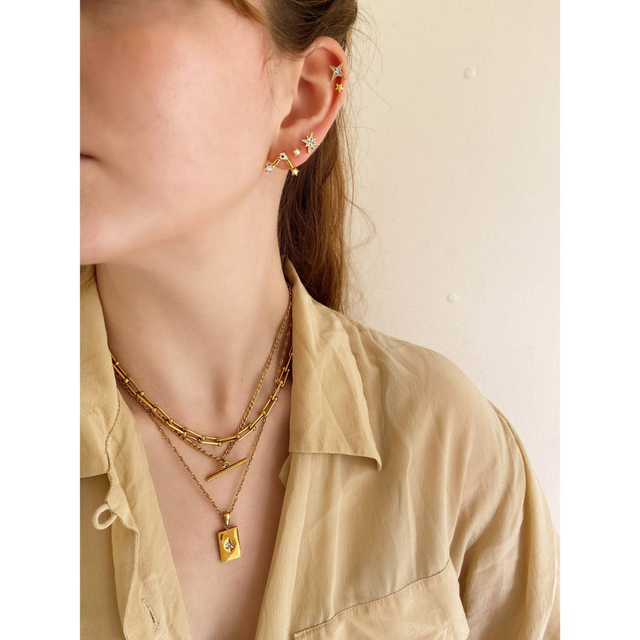 woman stacking gold jewellery with oversized shirt