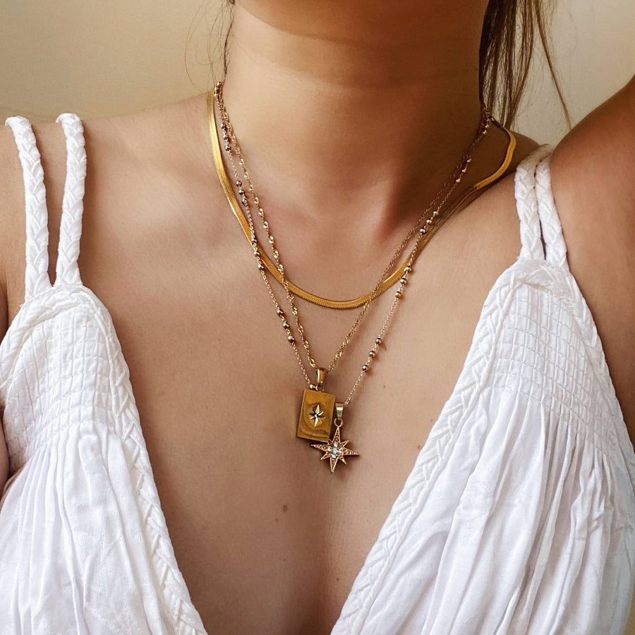 woman layering necklaces in gold
