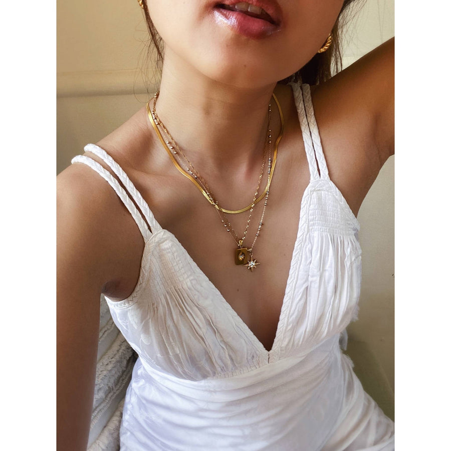 woman wearing gold necklaces with white dress