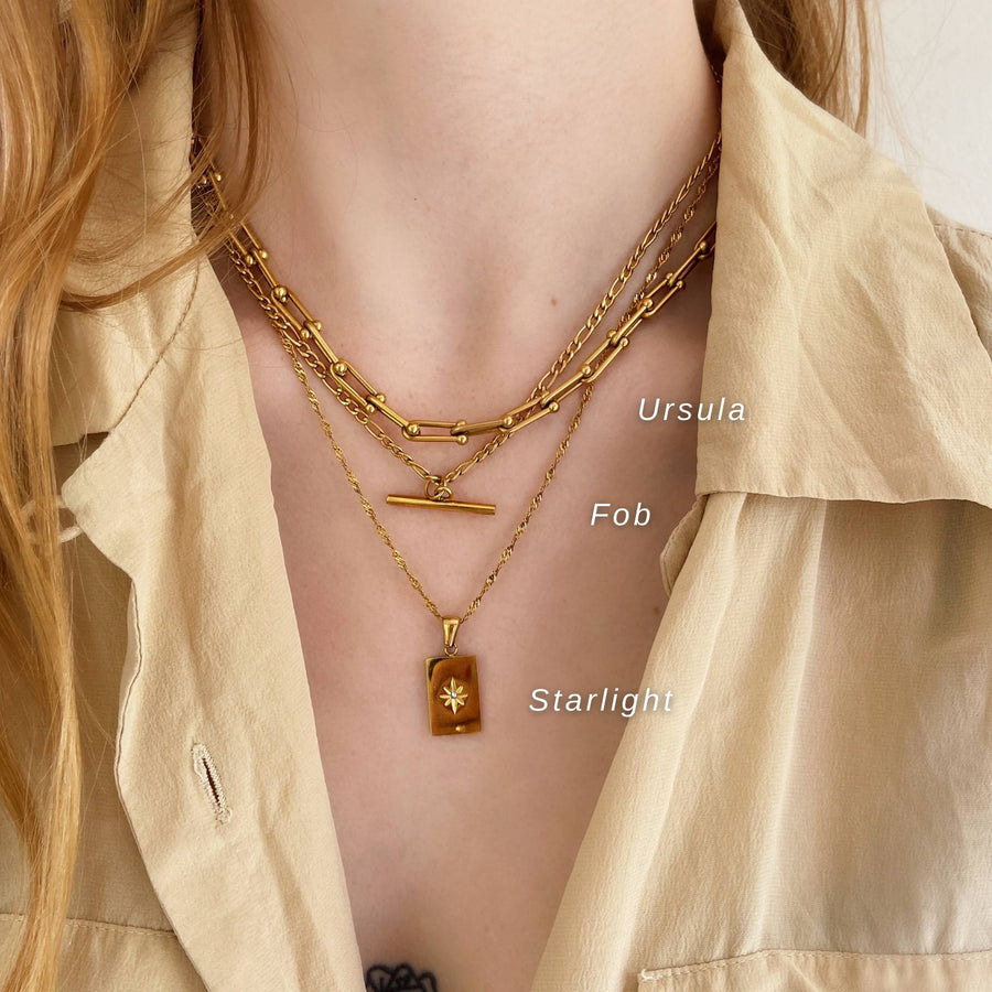 woman layering 3 gold necklaces
