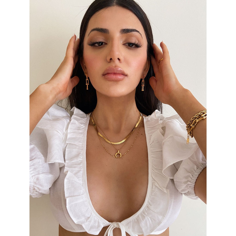 sexy woman wearing layered gold jewellery and cropped white top