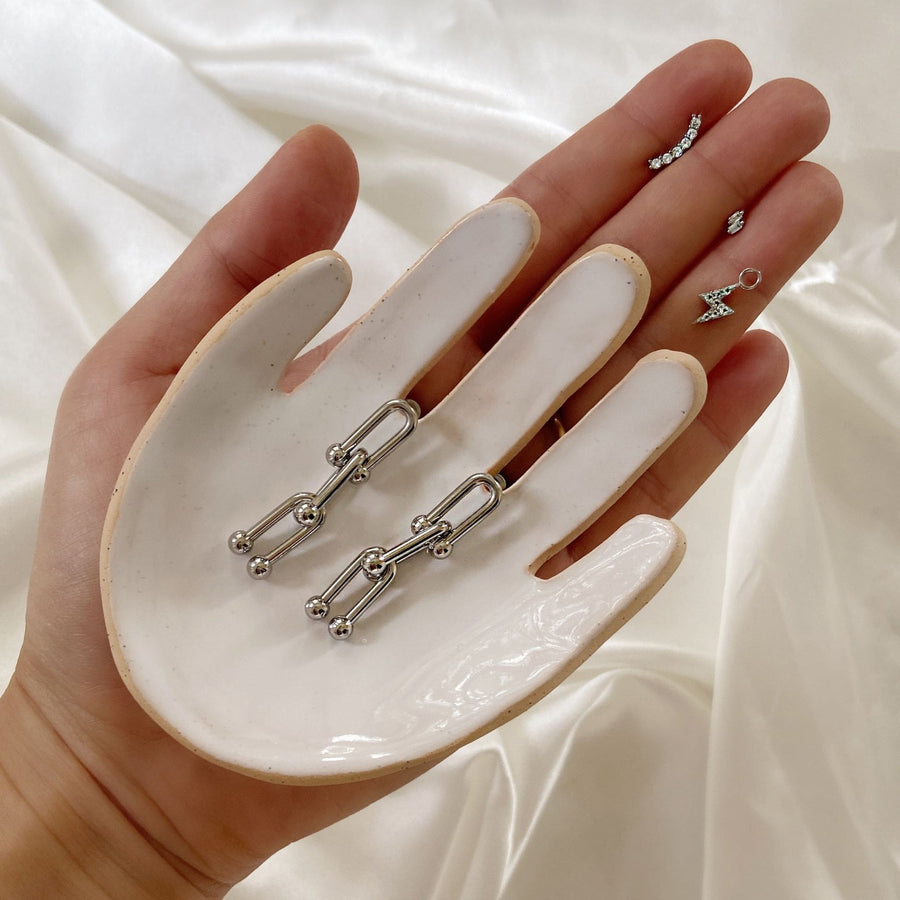silver link earrings on hand dish