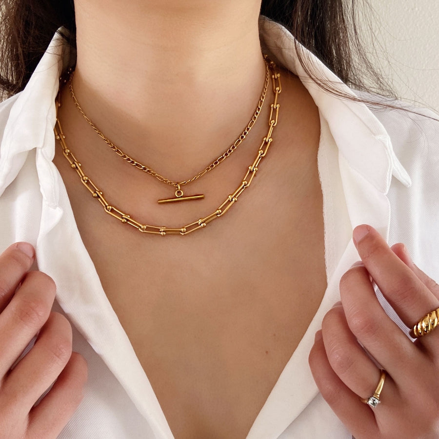 woman layering chunky gold necklaces