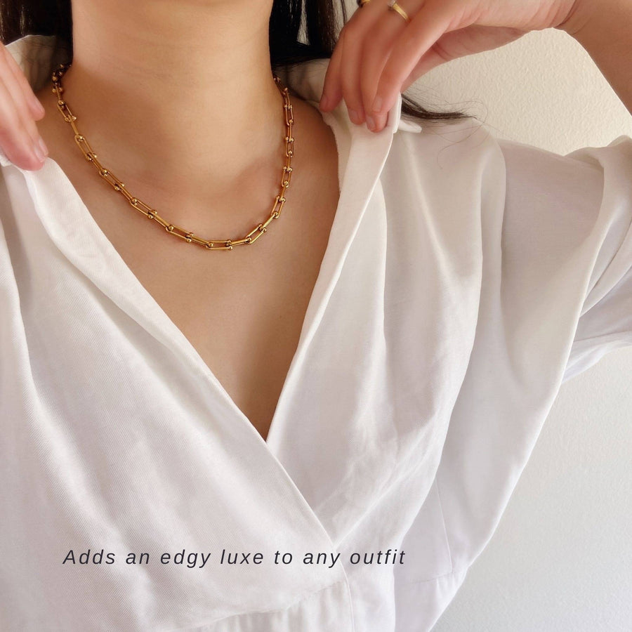 woman wearing chunky gold chain necklace and white shirt