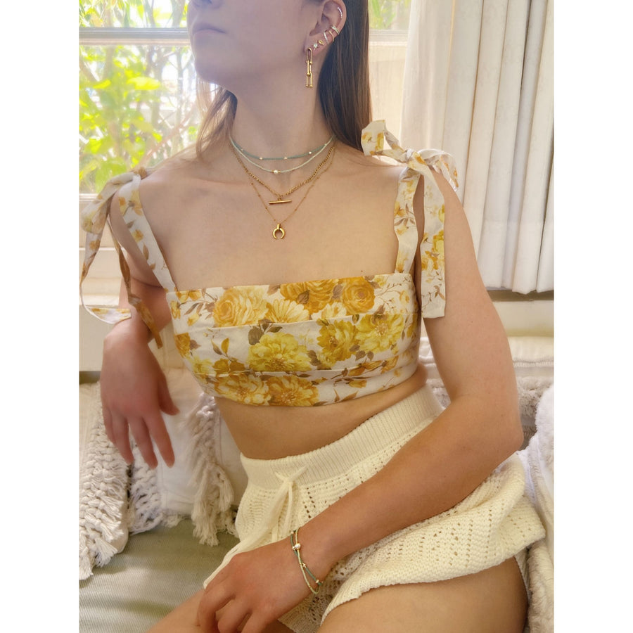 woman wearing yellow top and white shorts with gold stacking jewellery